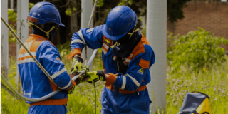 Imagen de dos técnicos de ENEL haciendo mantenimiento a unos cables de luz.
