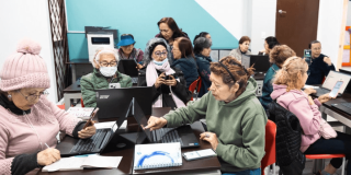 Mujeres mayores usando celulares y computadores. 