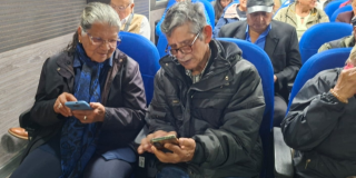Foto de dos adultos mayores mirando la pantalla de sus celulares 