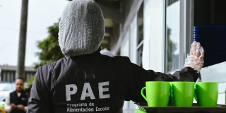 Foto de una mujer funcionaria del Programa de Alimentación Escolar (PAE), usando la indumentaria con el logotipo del programa.