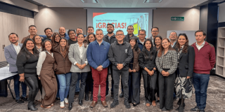 Grupo de profesionales posa para una fotografía en salón de reuniones tras misión de apoyo técnico a regiones afectadas por el sismo, con una pantalla al fondo que muestra el mensaje “¡GRACIAS!”
