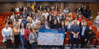 Grupo de personas reunidas en un auditorio con sillas rojas. En el centro de la imagen varias personas sostienen un tablero gigante con el texto: “Acuerdo de conservación. El agua que nos une”, junto a múltiples firmas