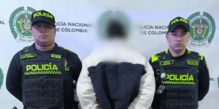 Hombre capturado, de espaldas, en medio de dos policías.