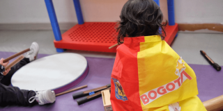 Foto que muestra un niño sentado con una bandera de Bogotá en la espalda