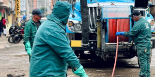 Imagen de un técnico del Acueducto realizando mantenimiento en un medidor de agua, de fondo se ve un carrotanque.