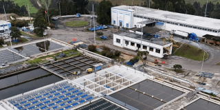 Foto que muestra una planta de tratamiento de aguas y edificios blancos en el fondo