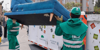 Foto que muestra dos personas dejando un mueble en un Ecopunto