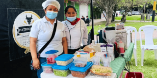 Foto que muestra dos mujeres sonriendo y una mesa con comida 