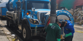 Foto que muestra personas con el uniforme del Acueducto de Bogotá junto a un carro vactor