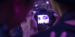 Imagen de una cámara fotográfica en cuyo lente se ven los ojos de una mujer