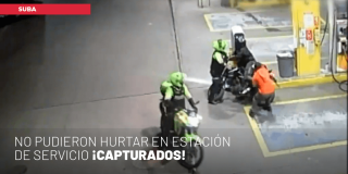 Policías capturando a dos hombres en estación de gasolina en Suba.