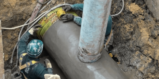 Foto que muestra dos personas del Acueducto de Bogotá reparando una tubería