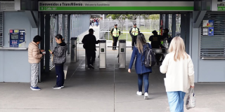 Foto de personas ingresando a una estación de TransMilenio usando su tarjeta para validar el pasaje.