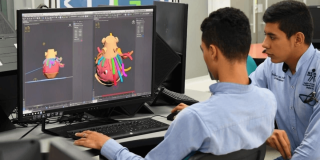 Foto que muestra dos personas trabajando frente a un computador 