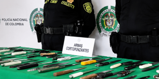 Foto que muestra dos policías y armas cortopunzantes en una mesa