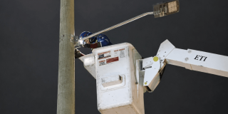 Foto que muestra una persona realizando labores de mantenimiento en un poste de luz 