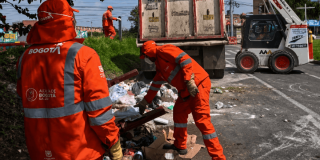 Foto que muestra dos personas con el uniforme de Aguas Bogotá levantando residuos 