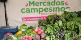Productos agrícolas frescos, entre ellos rábanos, remolachas, lechugas y otras hortalizas, exhibidos en un puesto de Mercados Campesinos Bogotanos