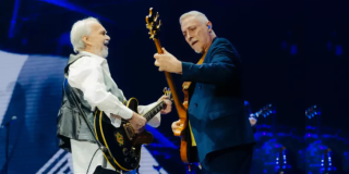 Imagen de dos hombres mayores tocan guitarra en un escenario.