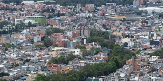 Vista panorámica de sectores residenciales y edificaciones de Bogotá, con viviendas de distintos tamaños distribuidas en una zona urbana rodeada de áreas verdes.