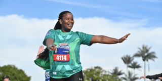 Persona participante de la Bimbo Global Race corre al aire libre con camiseta verde y dorsal 4114, con un brazo extendido durante la competencia.
