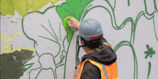 Imagen de un hombre dando la espalda que pinta un graffiti.