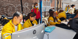 Foto que muestra hombres y mujeres trabajando frente a un computador