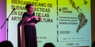 Imagen de una mujer hablando por un micrófono en una tarima 