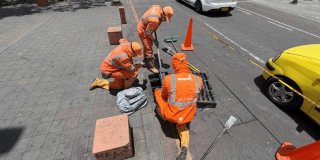 Foto que muestra tres personas con el uniforme de Aguas Bogotá limpiando un sumidero 