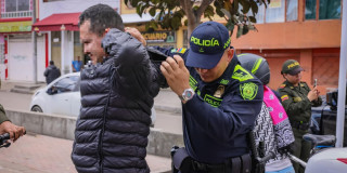 Foto de un uniformado de la Policía de Bogotá requisando a una persona durante la intervención en el parque Bellavista de Kennedy en Bogotá.