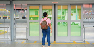 Foto de una mujer en una estación de TransMilenio frente a una de las puertas automáticas.