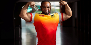 Foto de deportista de parapowerlifting mostrando su entrenamiento físico portando la camiseta del Equipo Bogotá color naranja.