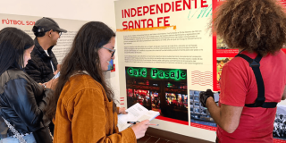 Imagen de personas al frente de cartelera historia Café pasaje en el centro de Bogotá