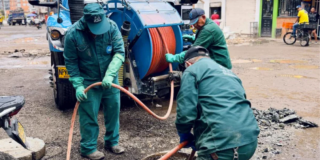 Imagen de varios técnicos de la Empresa de Acueducto haciendo mantenimiento a una tubería, de fondo se ve in carrotanque.