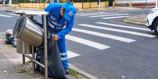 Foto que muestra una persona con el uniforme de LIME haciendo aseo en una caneca para basuras
