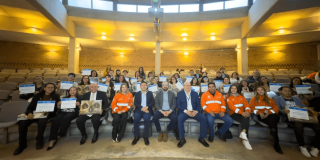 Foto que muestra un grupo de personas sentadas en un auditorio 