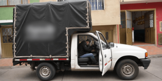 Camioneta del programa Foncarga de Bogotá estacionada con la puerta del conductor abierta y un módulo cubierto instalado en la parte trasera, frente a edificaciones urbanas.