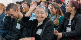 Foto de una señora levantando la mano 
