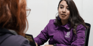 Foto de abogada de la SDMujer, con chaqueta morada, brindando atención jurídica.