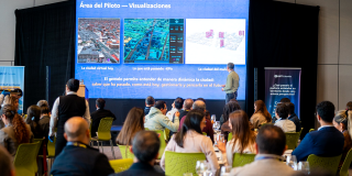 Foto de un foro académico donde los asistentes escuchan la presentación de un experto, quien proyecta una presentación.