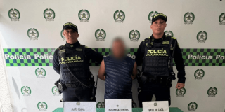Foto de hombre capturado en medio de dos policías.