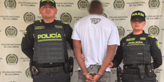 Foto de un hombre capturado en medio de dos policías.