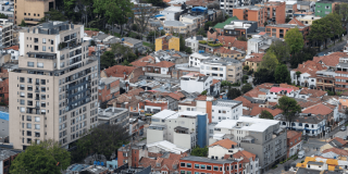 Vista aérea de un sector residencial y comercial de Bogotá, con edificios de mediana y gran altura, viviendas de teja roja y áreas arborizadas.