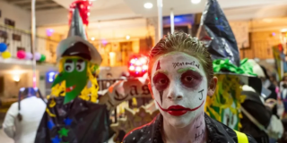 Imagen de un niño disfrasado con su cara pintada, de fondo se ven más niños disfrazados.