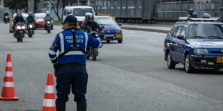 Foto de un agente de tránsito en una vía de Bogotá donde están varios vehículos