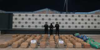 Foto de una persona capturada en medio de dos policías, con e cargamento de 700 kg de marihuana expuestos en el piso. 