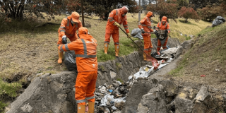 Foto que muestra personas con el uniforme de Aguas Bogotá limpiando las calles