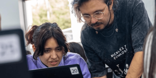 Una mujer y un hombre mirando la pantalla de un computador.