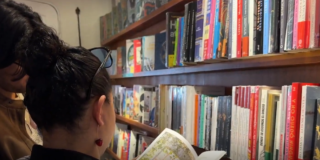 Imagen d eun holbre y una mujer leyendo un libro en una biblioteca.