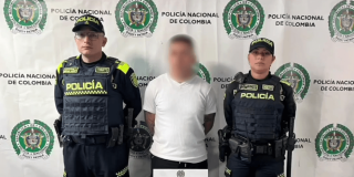 Foto de un hombre capturado en medio de dos policías.